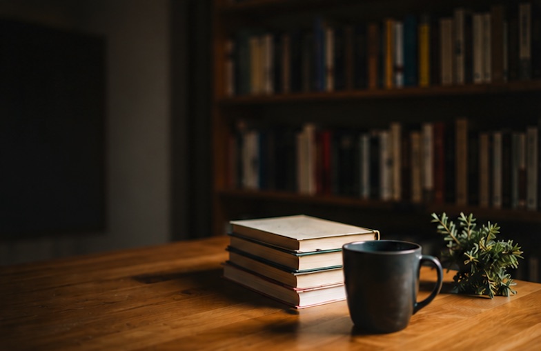 A stack of books beside a mug in a quiet library